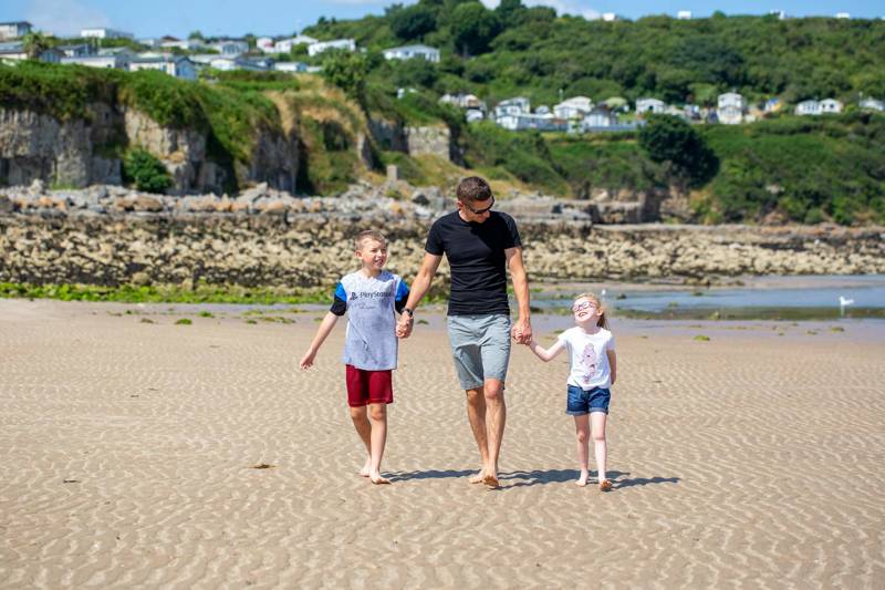 Dad with two children walking on the beach in Anglesey